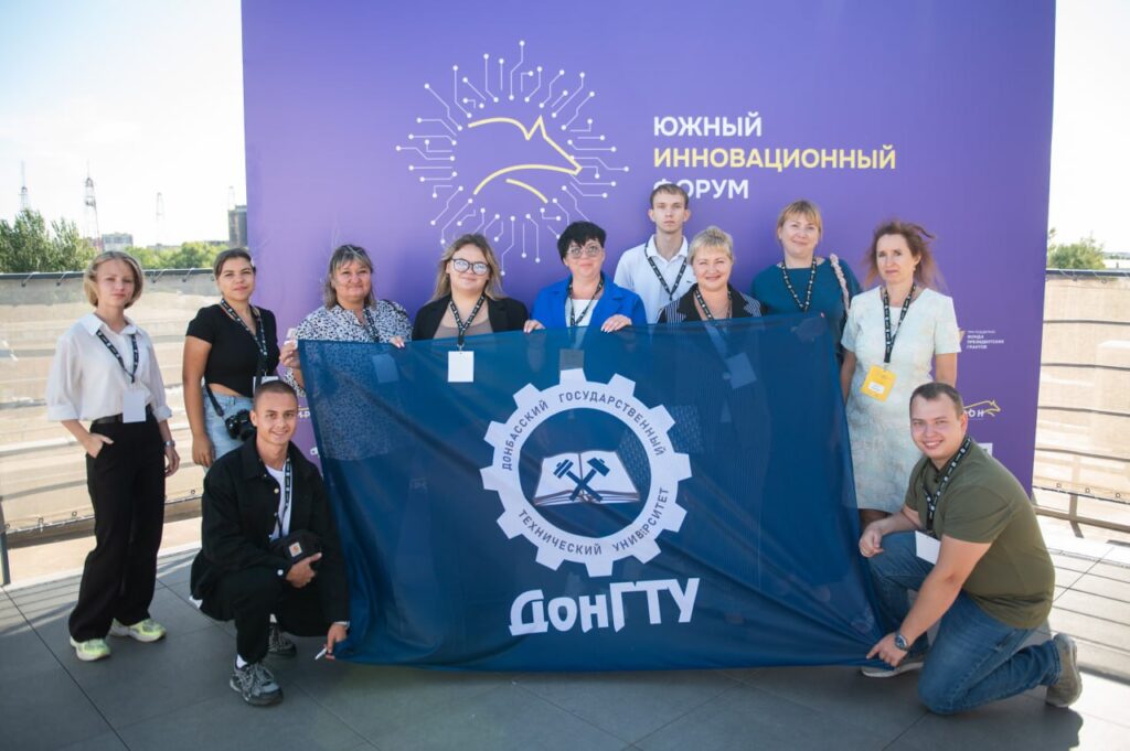 Участники форума стоят с флагом ДонГТУ на фоне баннера форума